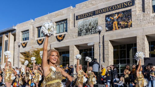Mizzou Golden Girls in gold uniforms perform with pom-poms in a Homecoming parade
