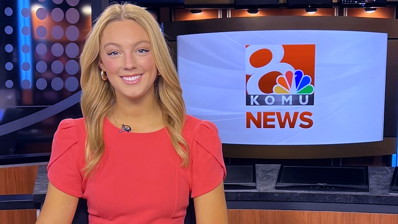 Charlotte Cicero posing at the news anchor's desk in front of the KOMU News graphic.