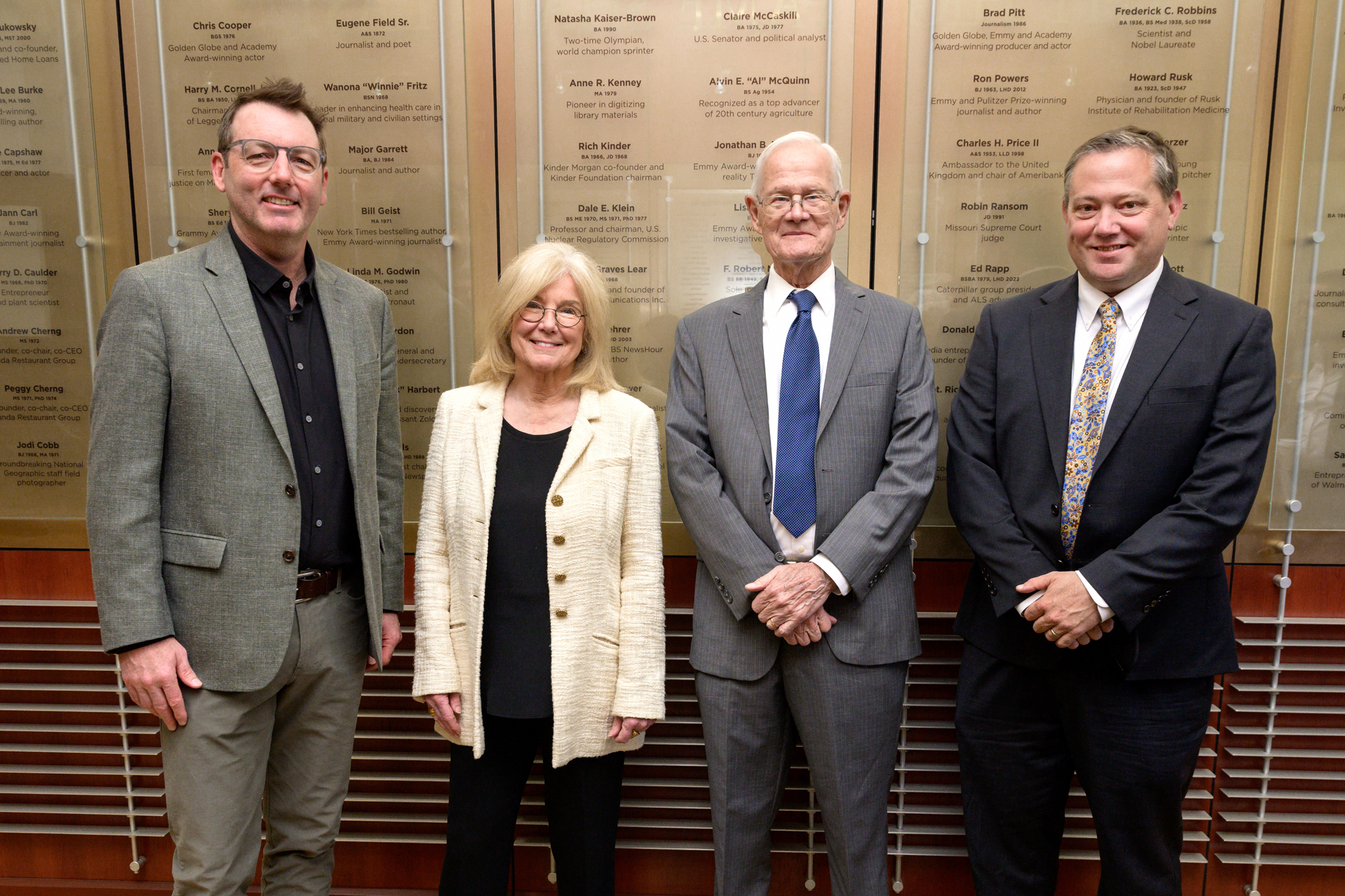 Golden Quill Alumni Excellence award recipients stand in front of the Notable Alumni Wall bearing the names of previous award recipients.