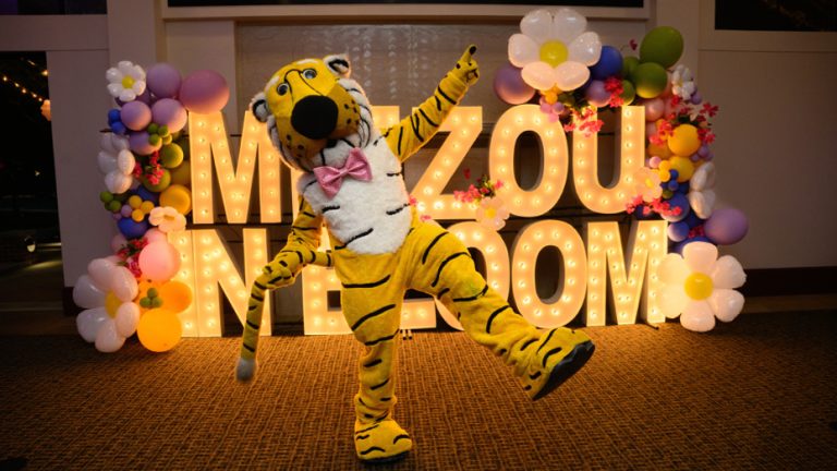 Truman the Tiger in front of Mizzou in Bloom sign